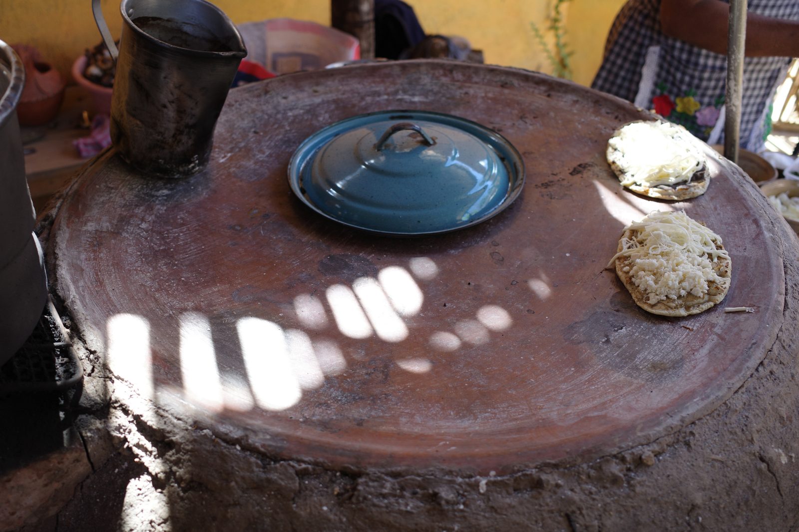 A comal — the round clay griddle set atop an earthen hearth — bakes the tortillas